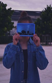 Close-up of woman holding picture frame against sky