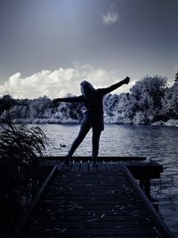 Rear view of man jumping on railing against sky