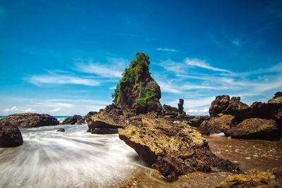 Rock formations by sea against blue sky