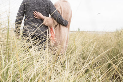 Midsection  rear view of man and woman holding each other in scenic place