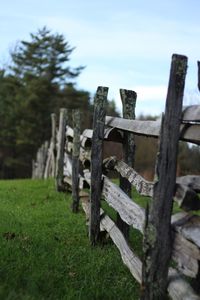 Wooden fence on field against sky