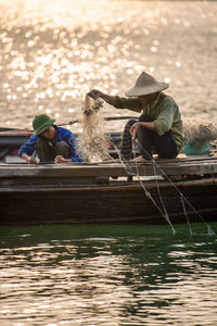 People sitting on boat against lake