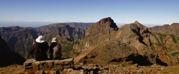 Rear view of couple sitting on mountain