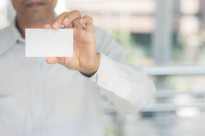 Midsection of businessman holding card in office