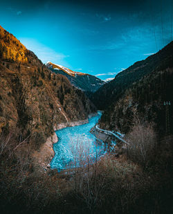 Scenic view of river amidst mountains against blue sky