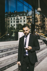 Businessman using smart phone while walking in city