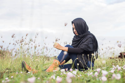 Side view of woman sitting on field