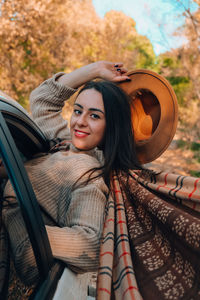 Portrait of young woman sitting on car