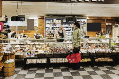 Sales clerk assisting woman while standing in supermarket