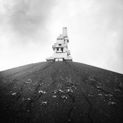 Low angle view of cross on rock against sky