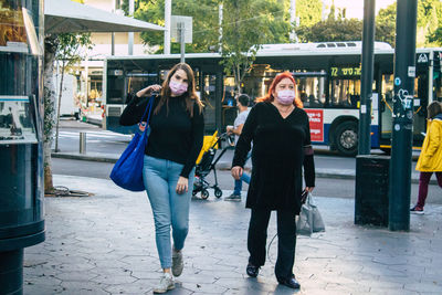 Full length portrait of young woman on footpath in city