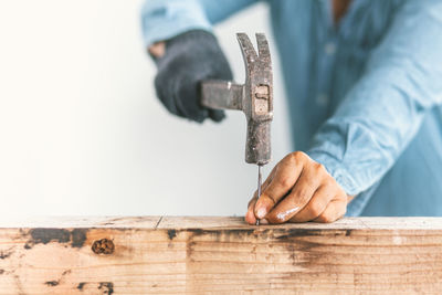 Midsection of man hammering nail on wood