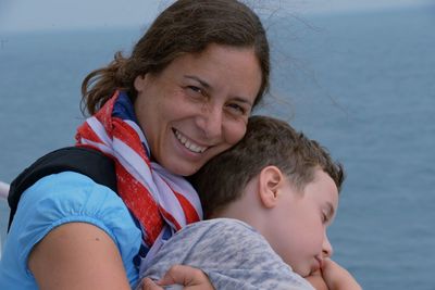 Portrait of smiling mother holding son at beach