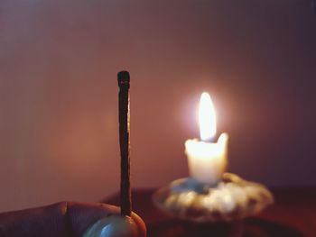 Close-up of hand burnt matchstick against candle