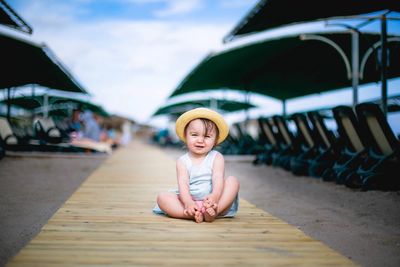 Portrait of girl sitting at beach against sky