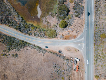 Top down aerial view of a t shaped road with some cars moving down the highway.