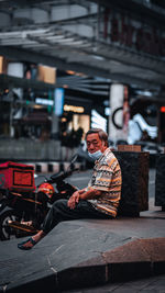 Man sitting on shopping cart in city