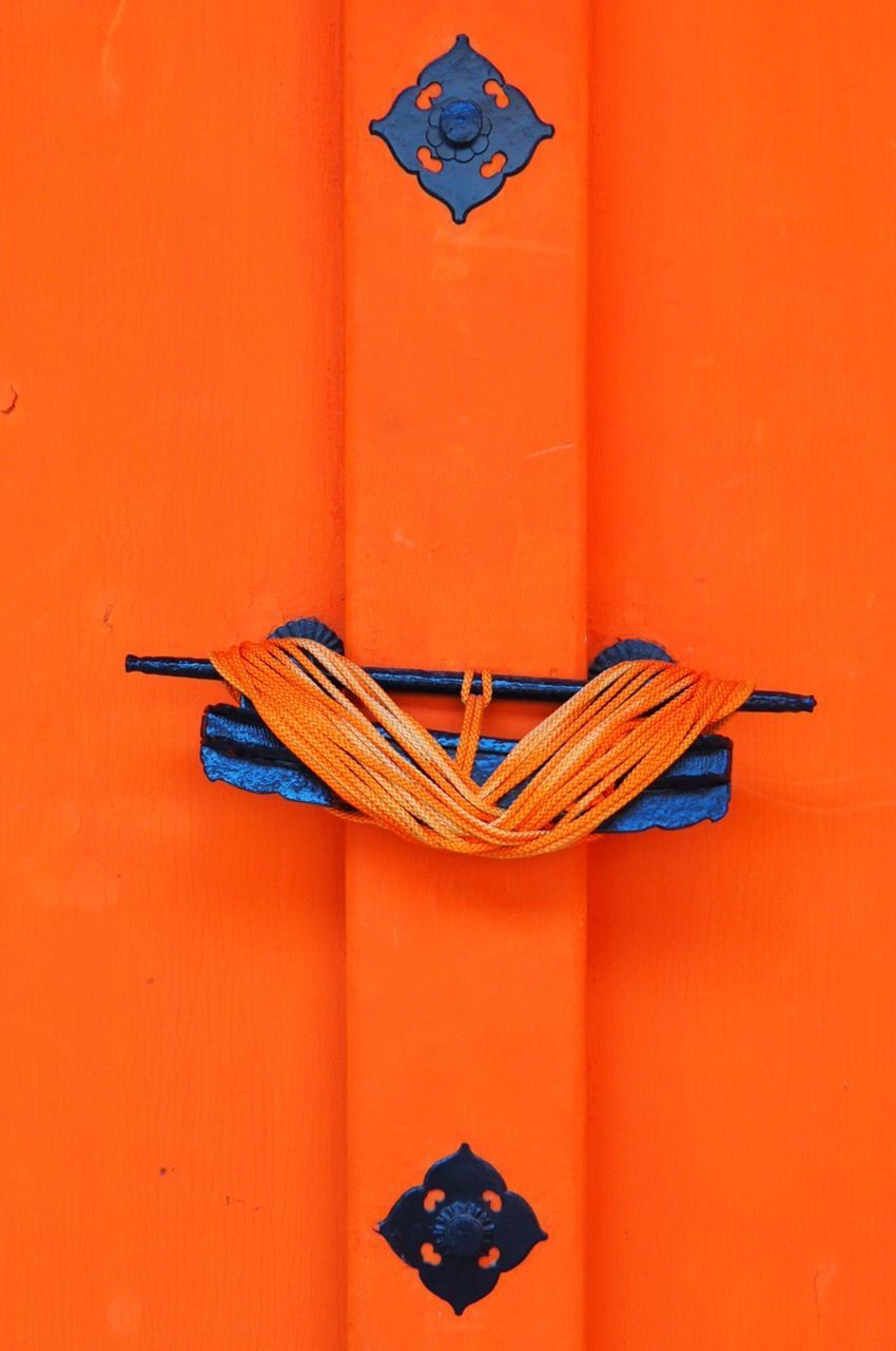 CLOSE-UP OF ORANGE LAMP AGAINST BUILT STRUCTURE