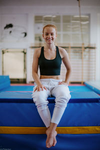 Smiling young woman sitting in gym