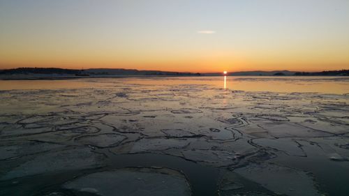 Scenic view of frozen lake during sunset