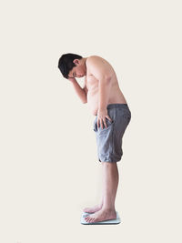 Full length of shirtless man standing against white background