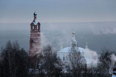 Buildings against sky during foggy weather