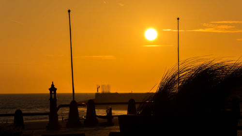 Silhouette man by sea against sky during sunset