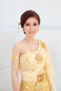 Portrait of a smiling young woman standing against wall