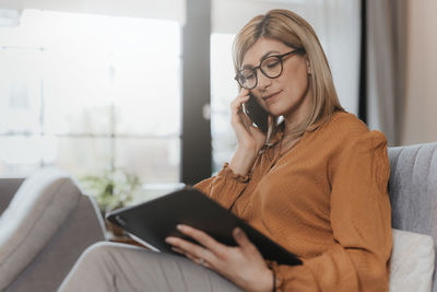 Businesswoman talking on phone while using digital tablet