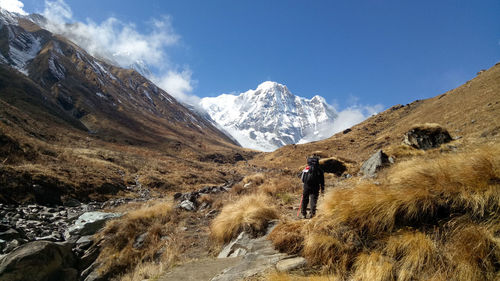 Man walking on snowcapped mountain against sky