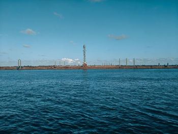 View of factory by sea against sky