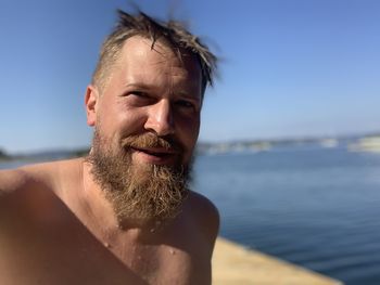 Portrait of shirtless bearded man by sea