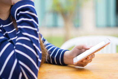 Midsection of person using mobile phone on table