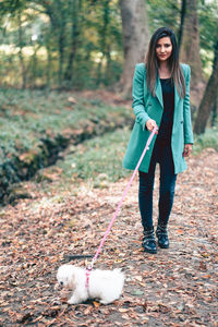 Portrait of young woman with dog standing on land