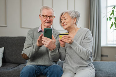 Friends using phone while sitting on sofa at home