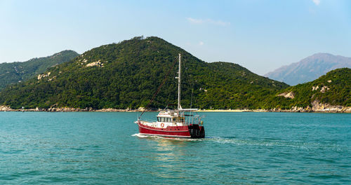 Boat sailing on sea against mountains