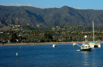 Boat sailing in sea by mountains against sky