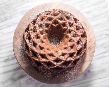 Hazelnut jubilee bundt cake on walnut stand against marble background