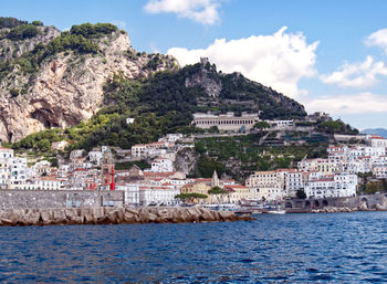 Buildings by sea against sky