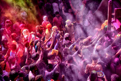 A hindu priest throws colourful powders  over devotees inside radhaballav temple of vrindavan 