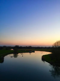 Scenic view of lake against clear sky during sunset