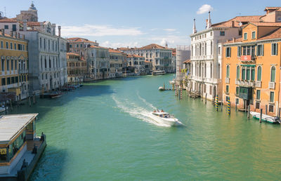 Boats in canal by buildings in city