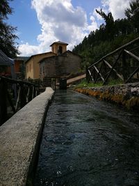 Bridge over canal amidst buildings against sky