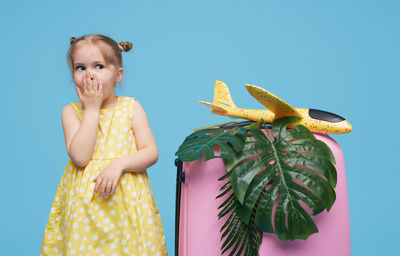 Close-up of cute girl standing against blue background