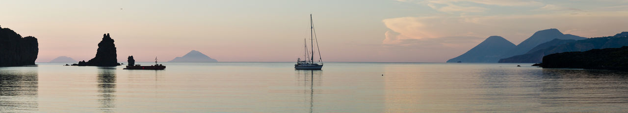 Boats sailing in sea against sky during sunset