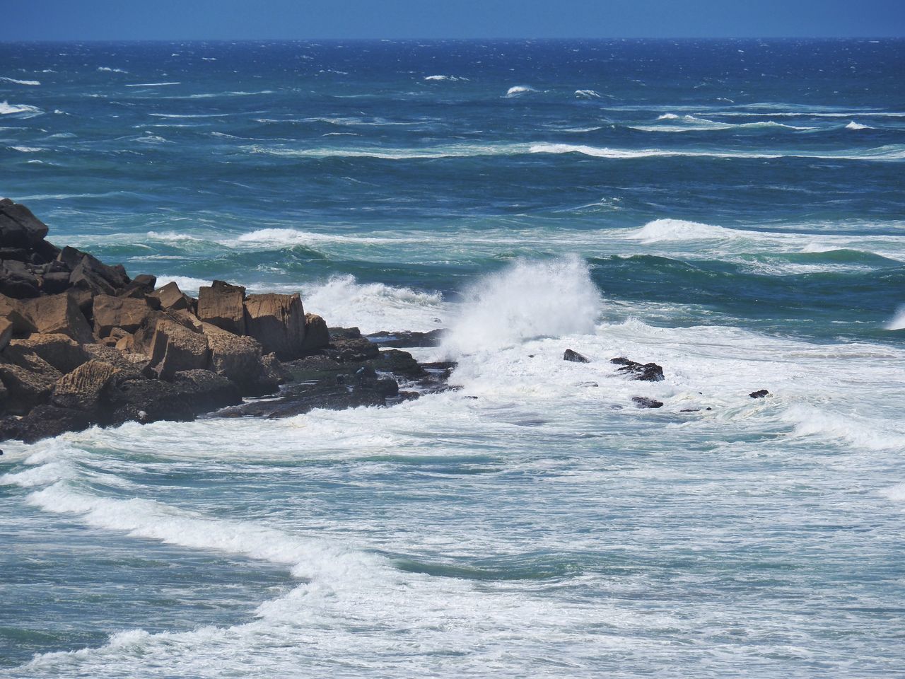 sea, water, wind wave, motion, wave, ocean, beauty in nature, shore, land, beach, sports, scenics - nature, coast, rock, water sports, surfing, nature, body of water, sky, splashing, outdoors, power in nature, breaking, horizon, day, blue, horizon over water, terrain, environment, cliff, rock formation