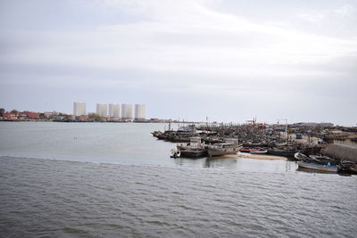 Nautical vessel on sea by buildings in city against sky