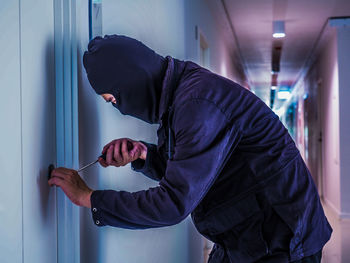 Side view of man standing against wall