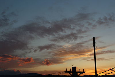 Low angle view of silhouette telephone pole against sky during sunset