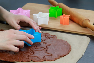 Cropped hands cutting cookies